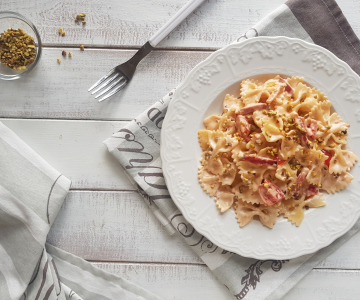 Farfalle with Parmesan cream, speck and pistachios