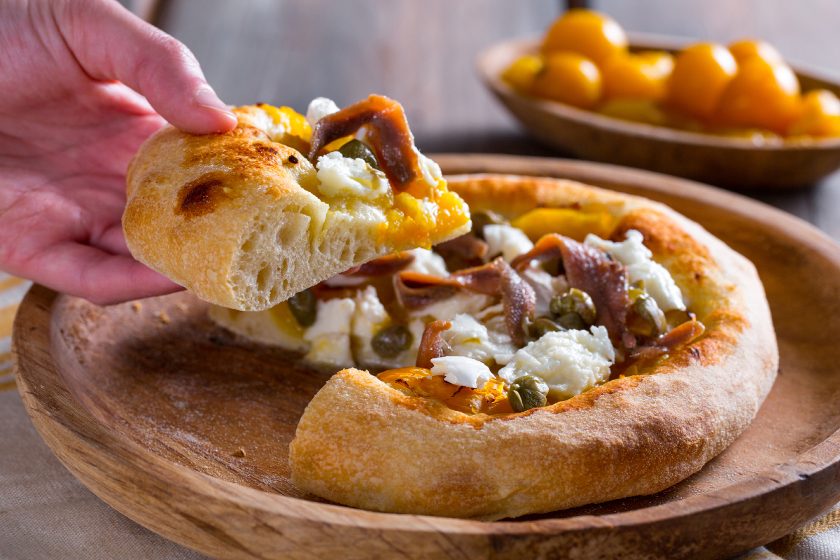 Pizza with yellow cherry tomatoes, anchovies, and capers