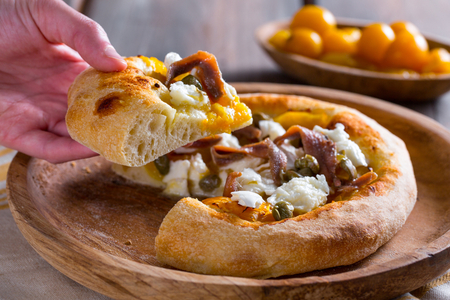 Pizza with yellow cherry tomatoes, anchovies, and capers