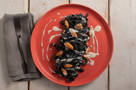 Tagliatelle with squid ink with pecorino, mussels, and lard