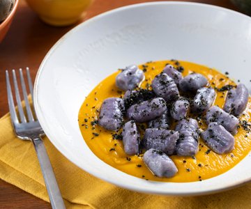 Purple potato gnocchi with pumpkin cream and black cabbage