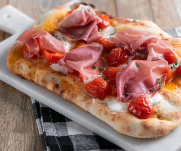 Pinsa with cured ham, cherry tomatoes and mozzarella