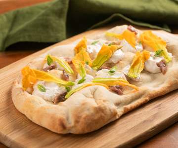 Pinsa with zucchini flowers, anchovies and cheese cream